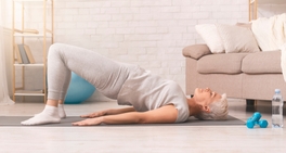An older woman practicing yoga on the floor.