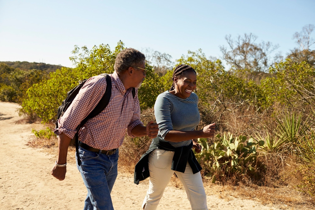 Two adventurers moving in unison on a hike down a dirt path.